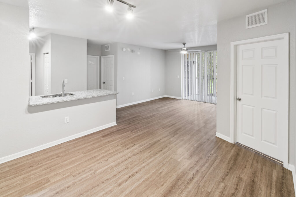 an empty living room and kitchen with white walls and wood flooring