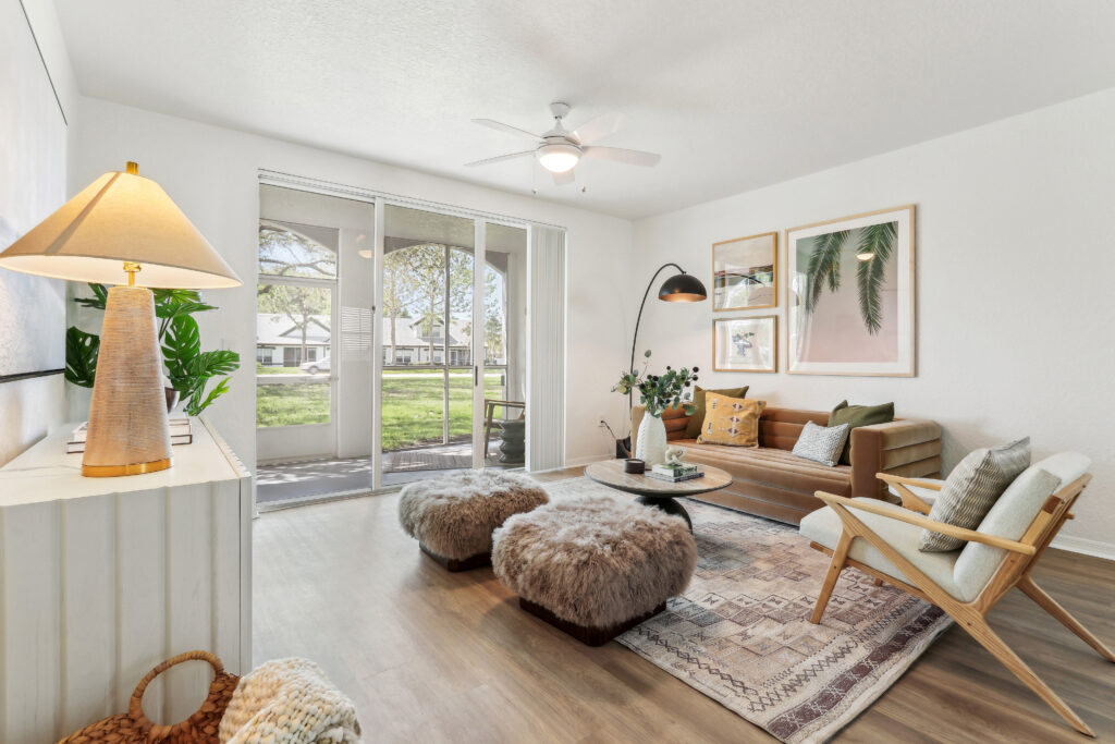 Living room with couch seating, ceiling fan, wood-style flooring, and access to the patio