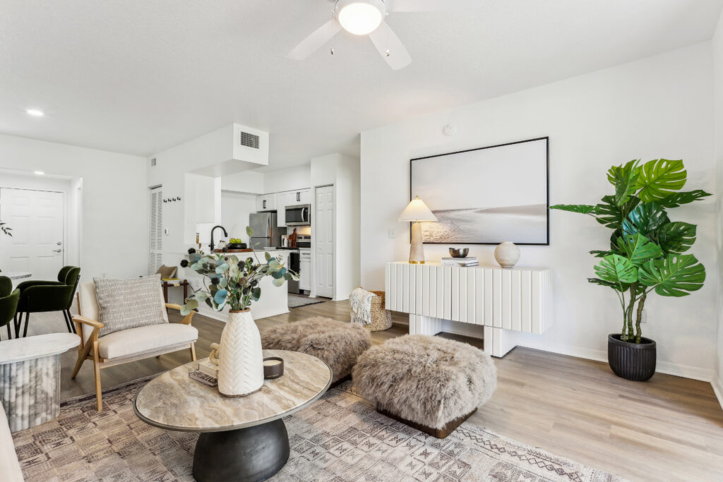 Living room with lounge seating, ceiling fan, wood-style flooring, and access to the kitchen