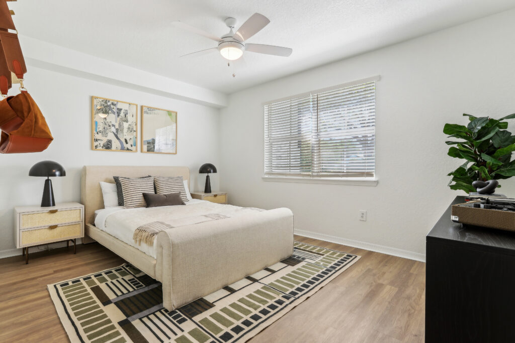 Bedroom with ceiling fan, wood-style flooring, window, and wall decor