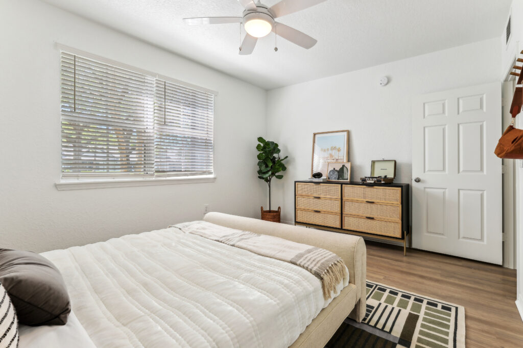 Bedroom with ceiling fan, wood-style flooring, window, and wall decor