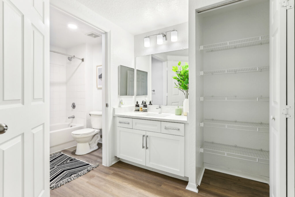 Bathroom with single sink, mirror, wood-style flooring, toilet, and tub/shower combo