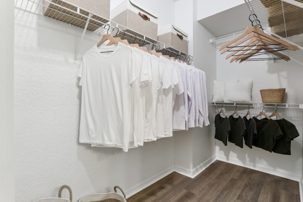 Large closet with clothes baskets, clothing, hangers, and wood-style flooring