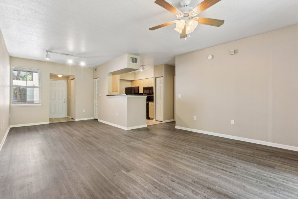 Open living room with ceiling fan, wood-style flooring, and open access to kitchen