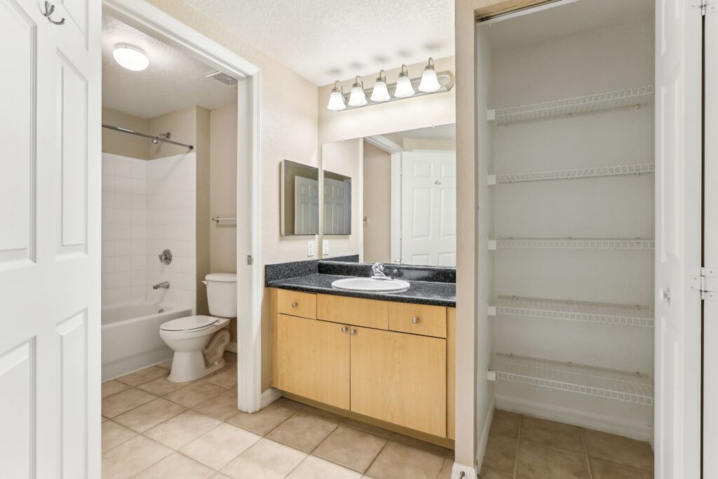 Bathroom with tile flooring, single sink, large mirror, toilet, and tub/shower combo