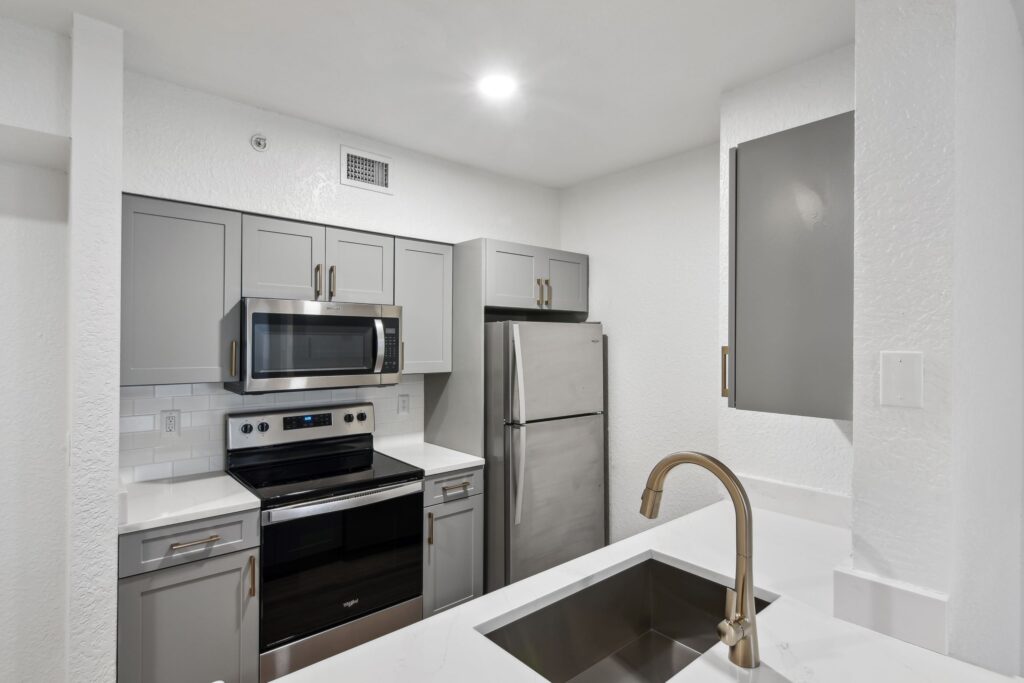 Kitchen with appliances, single sink, wood cabinets, and designer lighting