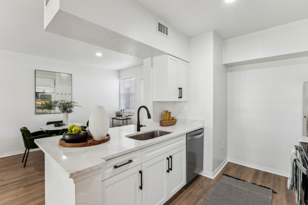 Kitchen with island sink, appliances, wood-style flooring, designer lighting, and open access to dining room